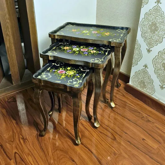 Close-up of Blossom Breeze nesting tables, highlighting the fine floral hand-painted details on a dark wooden surface with ornate edges