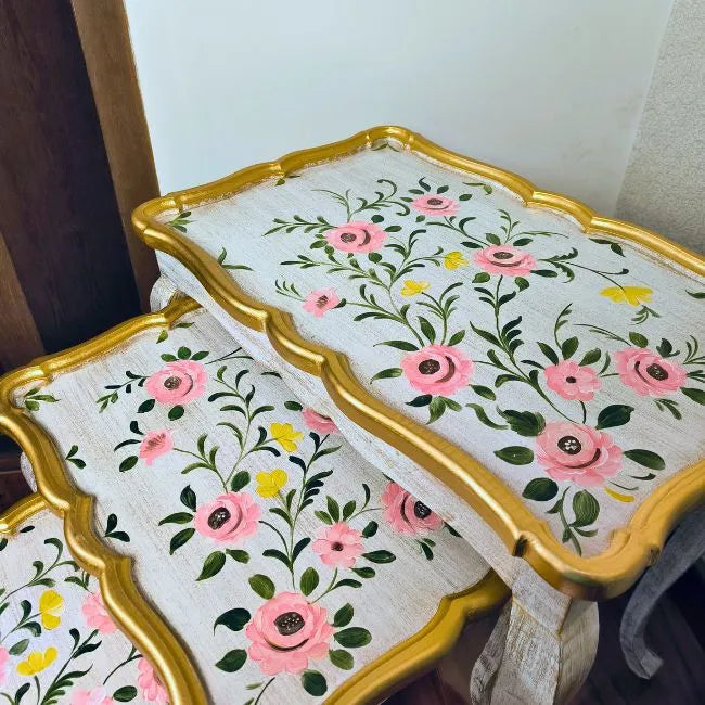 Side view of Pink Rose wooden nesting tables showcasing intricate hand-painted pink floral designs and a vintage white and gold finish.